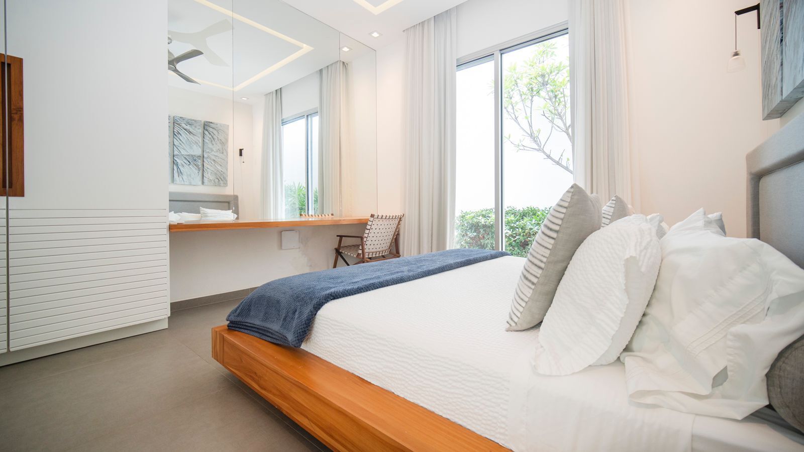 Une chambre moderne avec un grand lit, un bureau intégré et une vue sur la verdure.