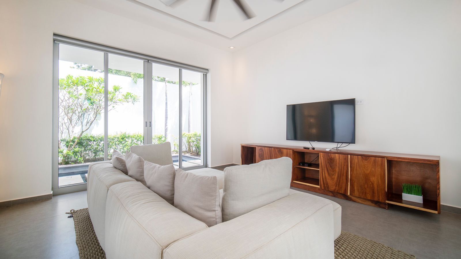 A modern living room with a sofa, a wooden entertainment unit, and a flat-screen TV.