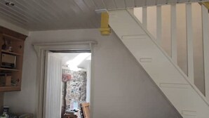 Una cocina con armarios de madera, una puerta blanca y una escalera con barandilla amarilla.