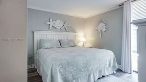Un dormitorio con una cama grande, una mesita de noche, una lámpara y decoración en la pared.