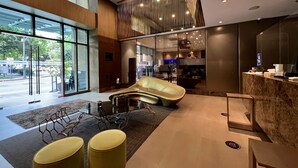 Una hall moderna con una zona salotto ad arco, una reception e ampie finestre con vista sulla strada.