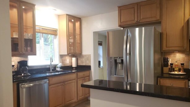 A modern kitchen with wooden cabinets, a stainless steel refrigerator, and a dishwasher. - Amazing Escape - 4 BEDS, 3 BEDROOMS, Private Deck near DC (Annandale)