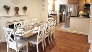 A dining area with a wooden table set for six, white chairs, and a fireplace. - Amazing Escape - 4 BEDS, 3 BEDROOMS, Private Deck near DC (Annandale)