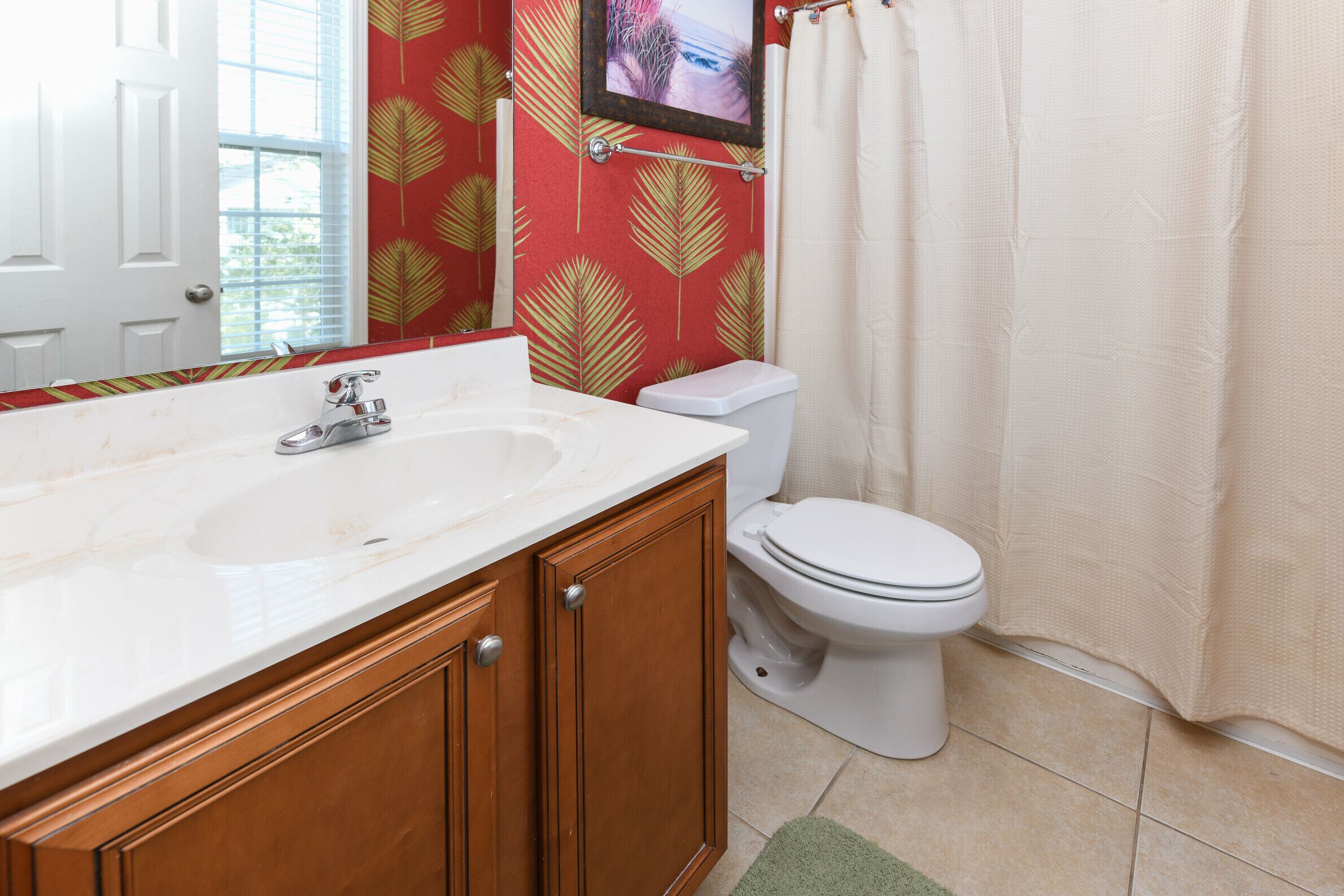 A bathroom with a white sink, wooden cabinets, a toilet, and a shower curtain.