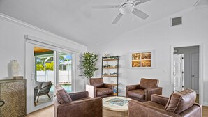 A spacious living room with a ceiling fan, a coffee table, and brown leather sofas. - Private Heated Pool | 5 Min to Beach | Bikes + Fire Pit (Marco Island)