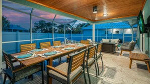 An outdoor dining area with a wooden table set for six, surrounded by chairs with cushioned seats. - Private Heated Pool | 5 Min to Beach | Bikes + Fire Pit (Marco Island)