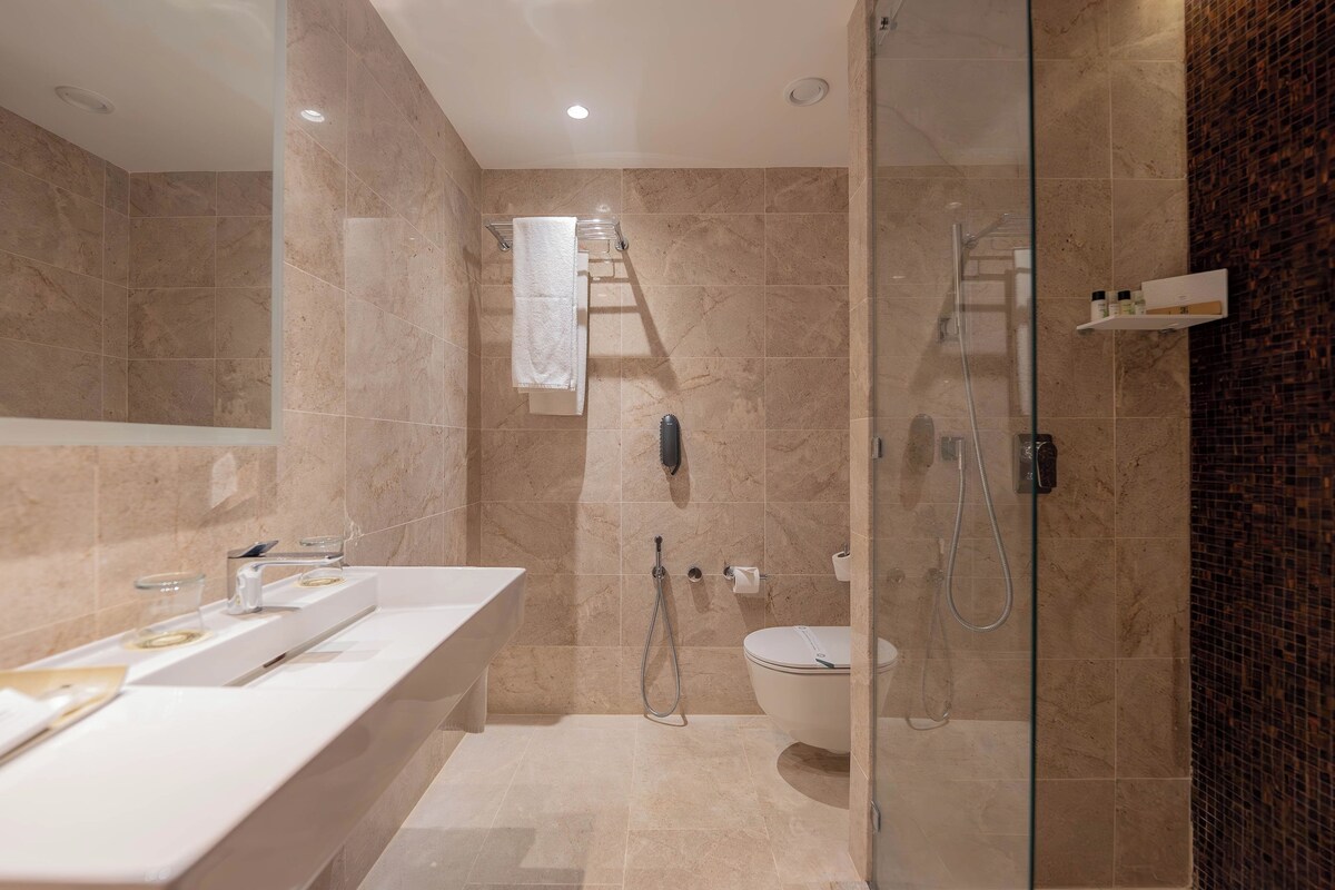 A modern bathroom with a glass-enclosed shower, a white sink, and a toilet.