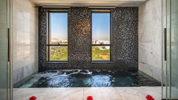Une salle de spa dotée d’une grande fenêtre, offrant une vue sur la ville, et dont le sol est recouvert de marbre.