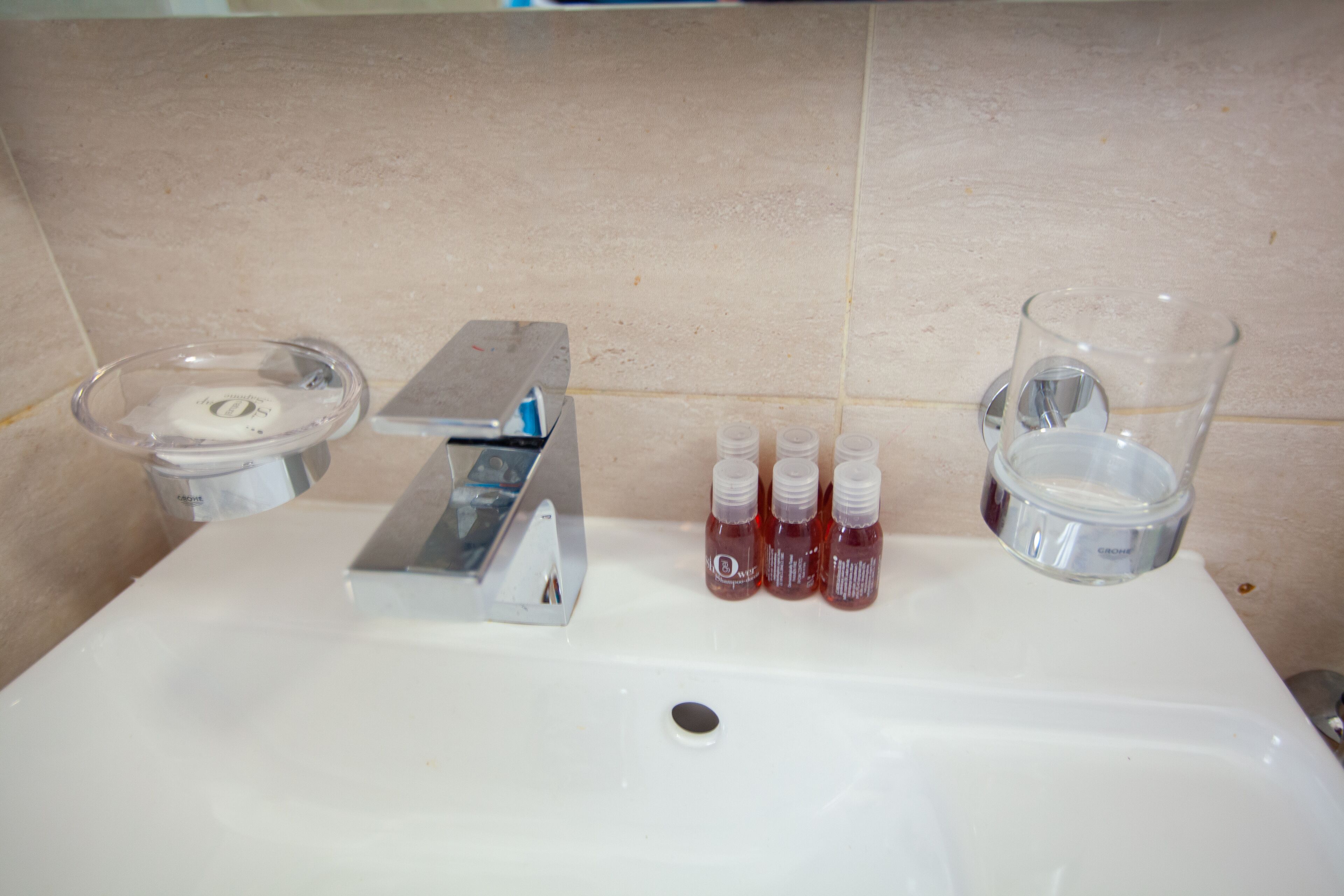 A bathroom sink with a soap dispenser, a razor holder, and several bottles of mouthwash.