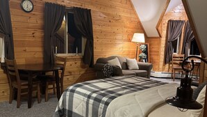 A cozy, log cabin-style bedroom with a bed, a desk, and a chair. - Lodge Suites at Susitna River Lodge (Talkeetna)