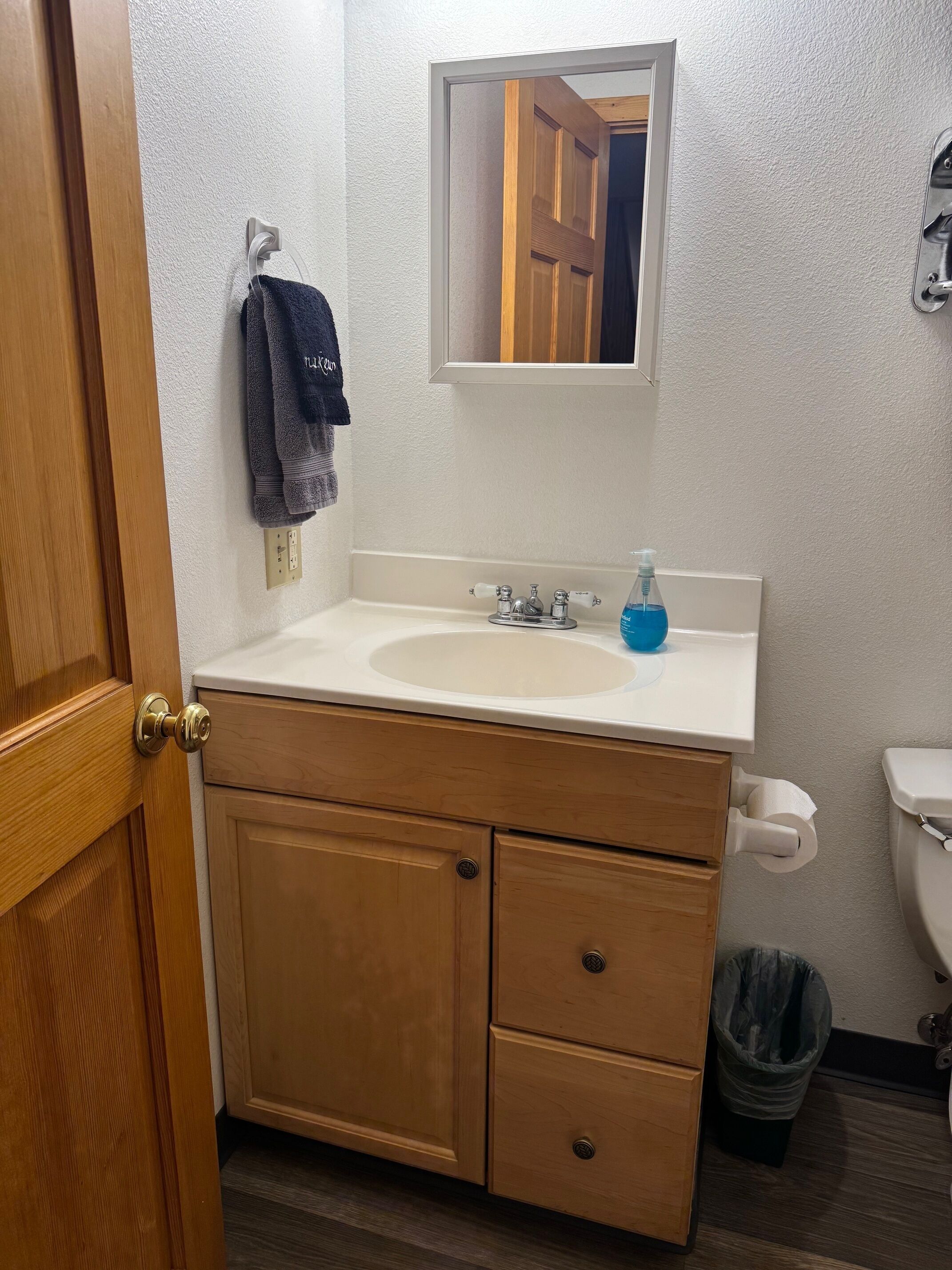 Un baño con tocador de madera, lavamanos, espejo y retrete.