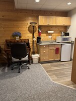 Una cocina compacta con armarios de madera, microondas, cafetera y refrigerador pequeño.