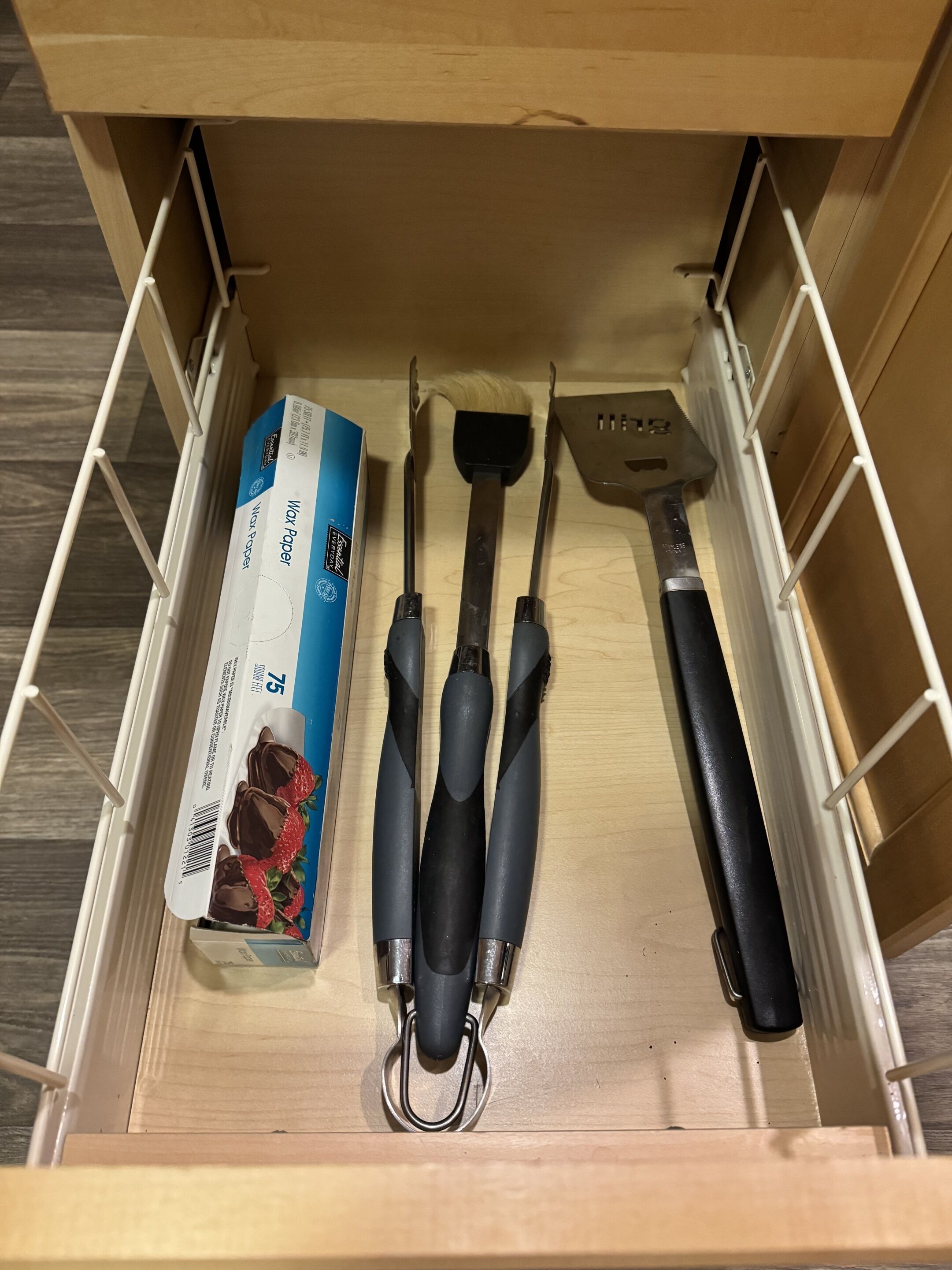 A drawer with wax paper, a spatula, and a box of chocolate.