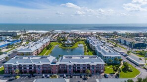 A coastal hotel with multiple buildings, a central courtyard, and a view of the ocean.