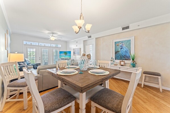 A dining area with a wooden table, white chairs, and a chandelier.