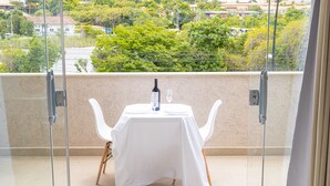 A balcony with a table set for two, a bottle, and a glass. - Apart Lagoa Buzios- Centro (Búzios)