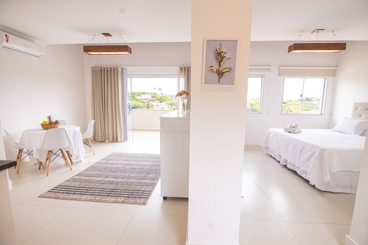 A hotel room with a dining area, a bed, and a view of the outdoors.