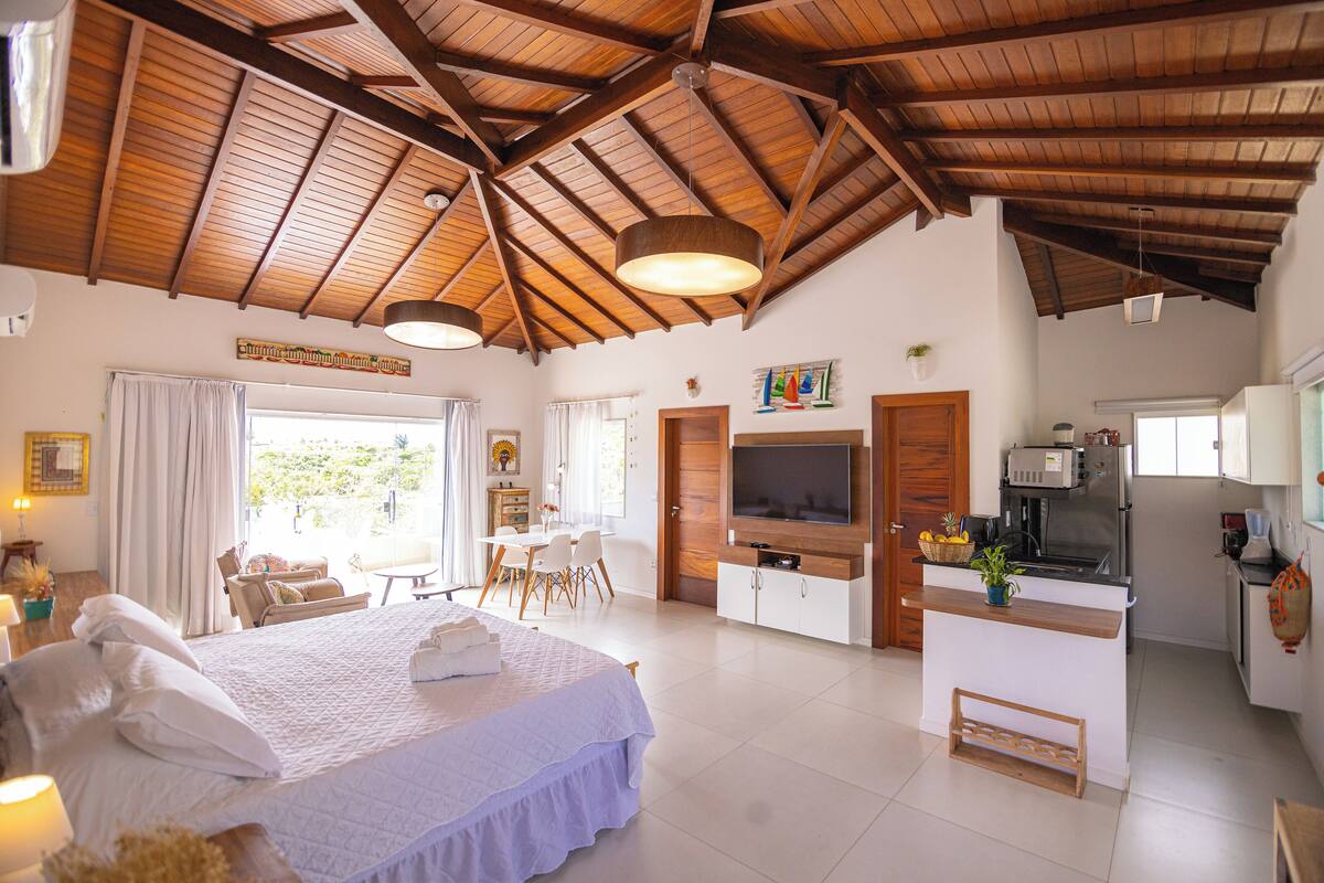 A spacious room with a large bed, a dining area, and a kitchen with a TV.