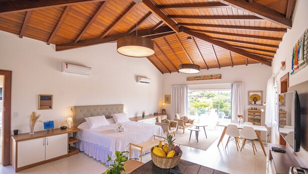 A spacious bedroom with a large bed, a dining area, and a kitchen. - Apart Lagoa Buzios- Centro (Búzios)