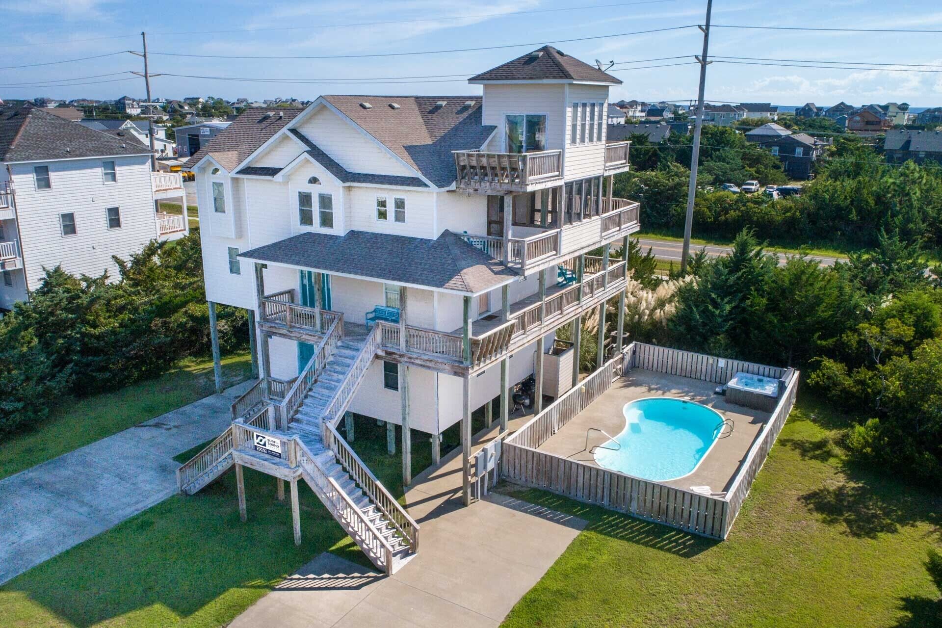 A multi-story house with a pool and a staircase leading to the upper levels.