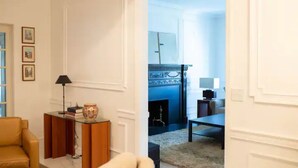 A living room with a fireplace, a sofa, a coffee table, and a side table with a lamp and books.