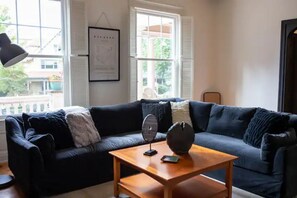A living room with a dark blue sofa, a wooden coffee table, a floor lamp, and a framed map on the wall.