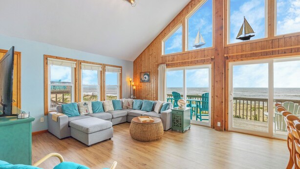 A spacious living room with a large sectional sofa, a round coffee table, and a view of the ocean through large windows. - Oceanfront Dog Friendly Home w/ Hot Tub and Nearby Beach Access (Avon)