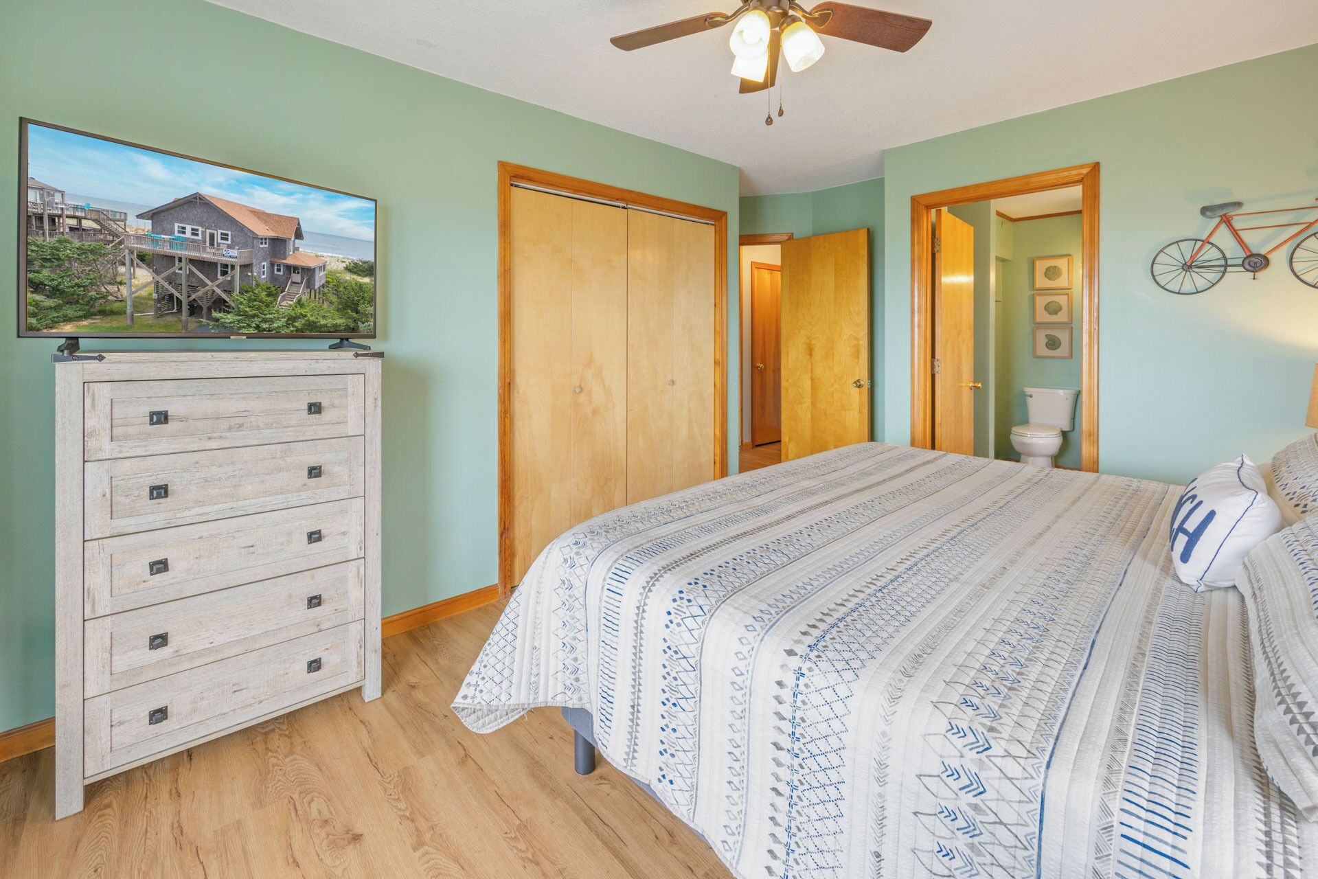 A bedroom with a bed, dresser, and a ceiling fan.