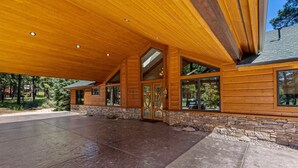 Une maison en rondins de style moderne, dotée d’un grand patio couvert et de fondations en pierre.
