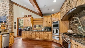 Une cuisine spacieuse avec des meubles en bois, un mur d’accent en pierre et une grande cuisinière.