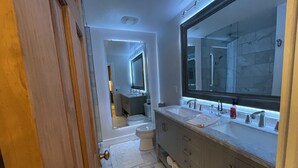 A modern bathroom with a large mirror, dual sinks, and a toilet. - Marble Studio (Highlands)
