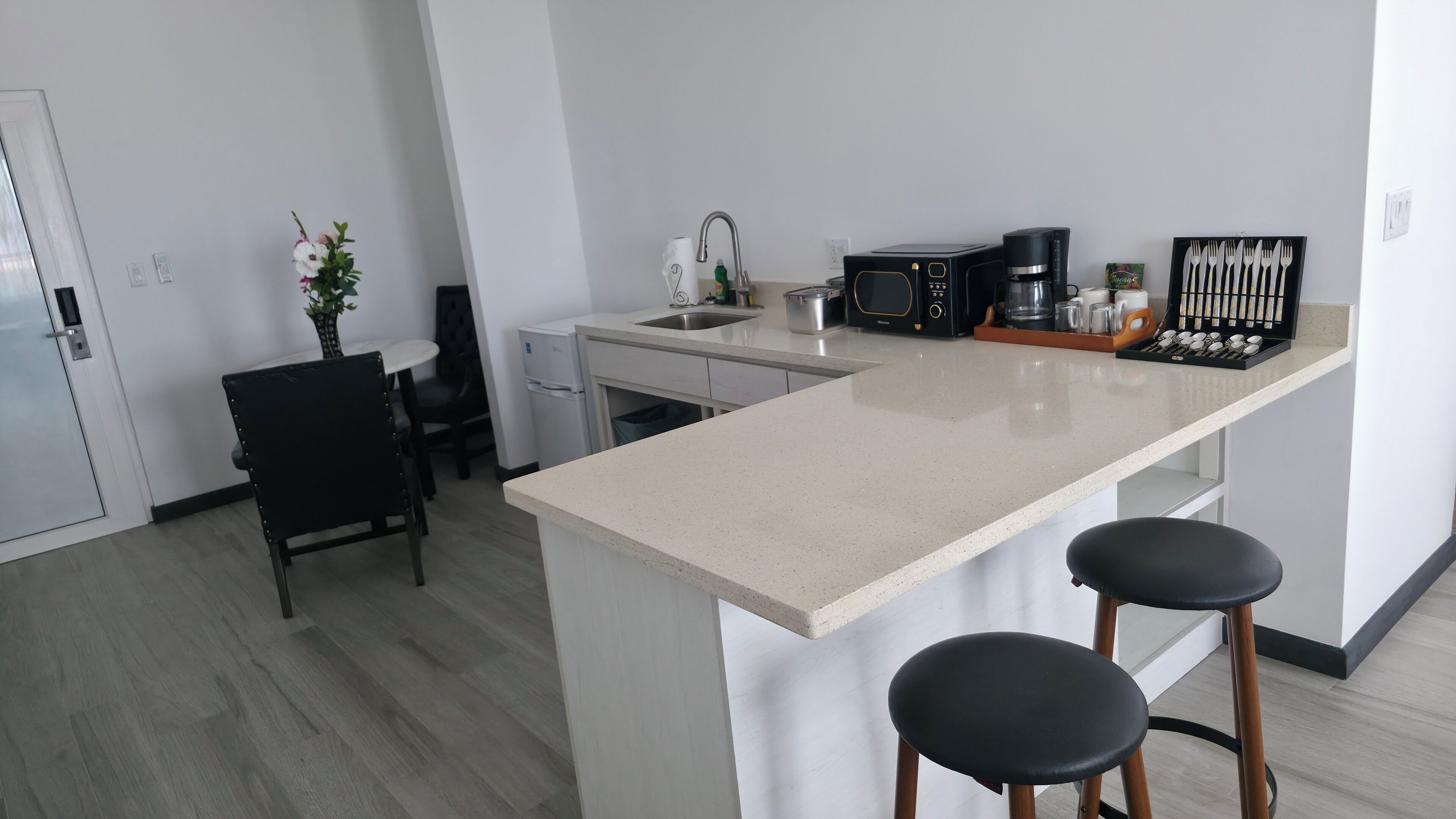 A modern kitchen with a central island, a microwave, a coffee maker, and bar stools.