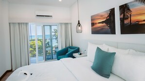 A hotel room with a large bed, a blue armchair, a nightstand, and a view of the ocean through a sliding door. - The Watermark Hotel (San Pedro)