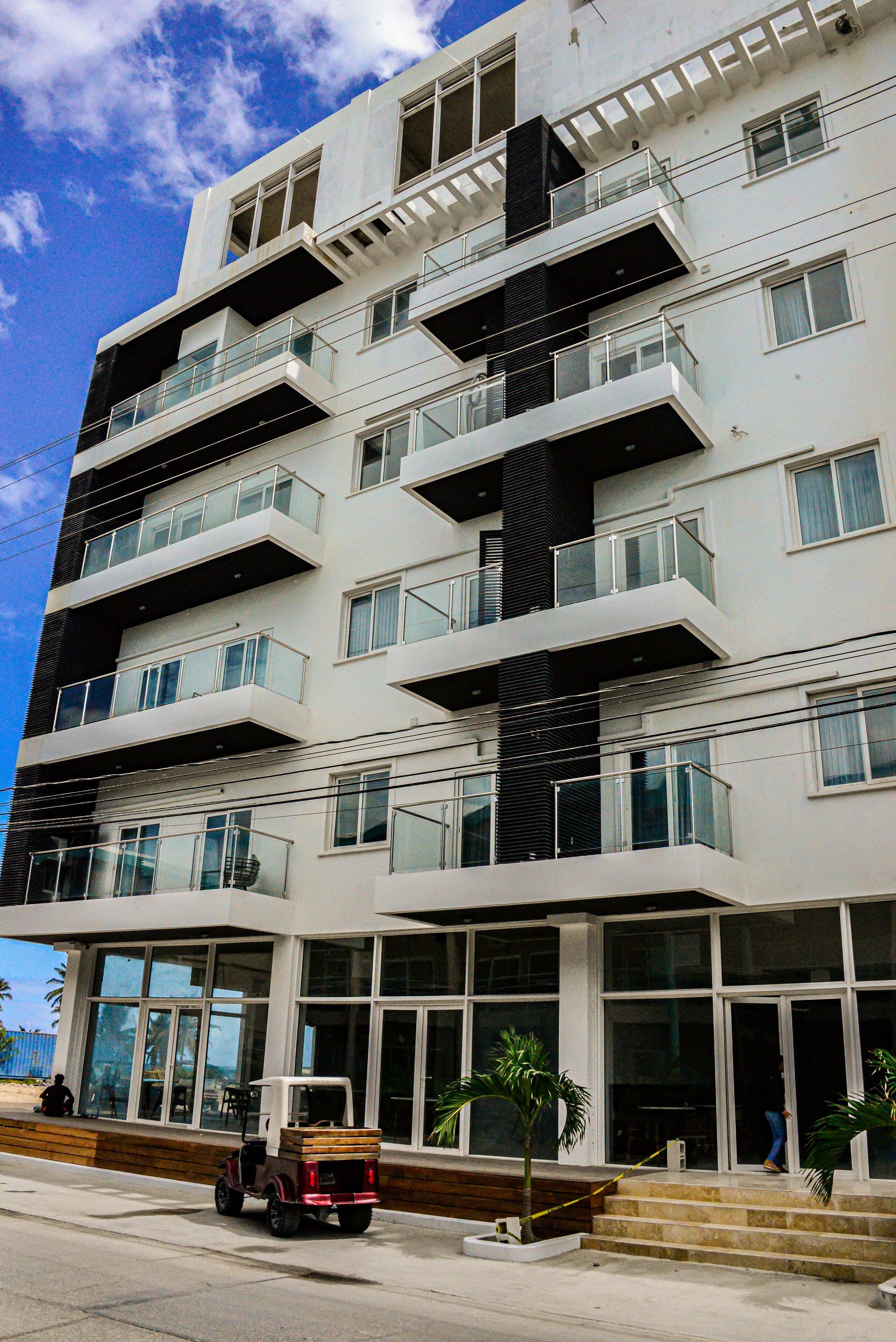 Un edificio a più piani con balconi, ampie finestre e un veicolo parcheggiato di fronte.