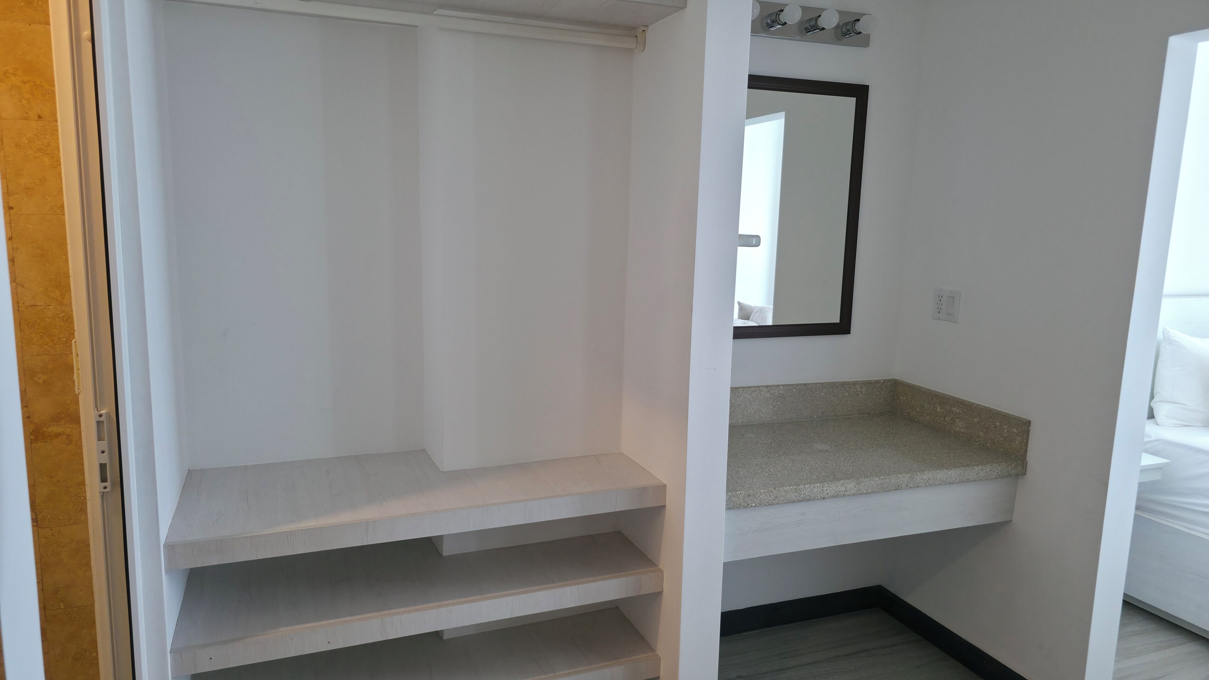 Un baño con tocador blanco, un espejo y zona de ducha.