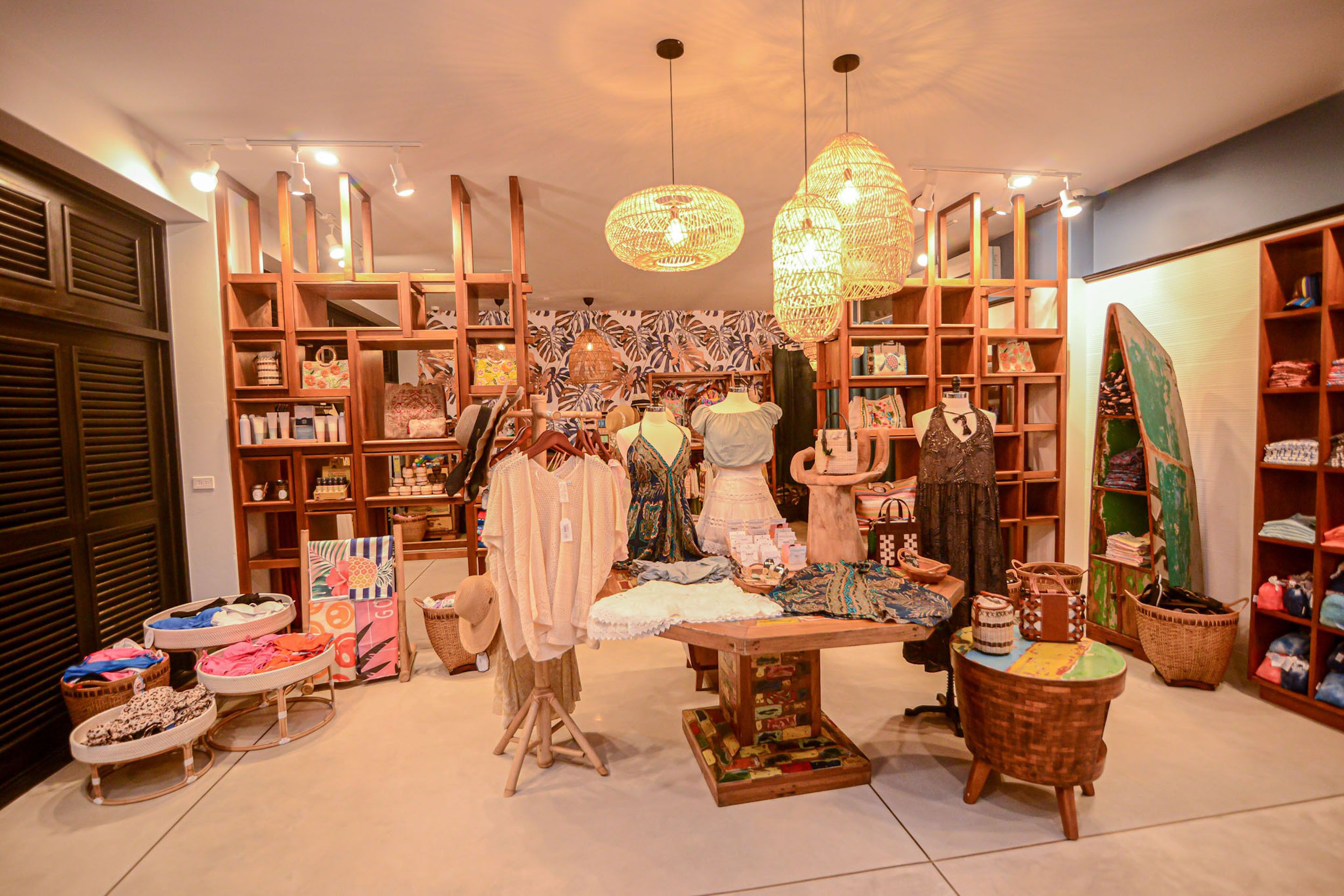 A boutique store with wooden shelving, hanging lights, and various textiles and accessories.