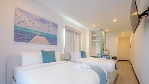 A hotel room with two beds, a painting of a seascape, a desk with a chair, and a TV mounted on the wall. - The Watermark Hotel (San Pedro)