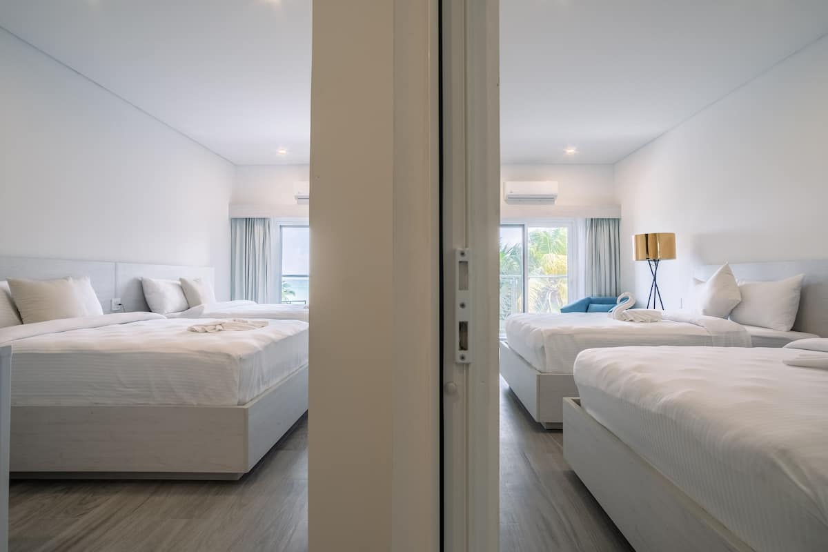 Habitación de hotel con dos camas, un ventanal grande y vistas a la vegetación.