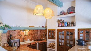 Een keuken met een tegel achterwand, houten kastjes en hangende lampen.