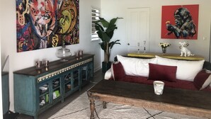 Een woonkamer met een blauwgroene kast, een houten salontafel, een rode bank en twee schilderijen aan de muur.