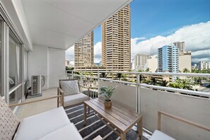A balcony with a sofa, a table, and a potted plant. - Contemporary City View One Bedroom Condo at the Ilikai w/King Bed & AC! (Honolulu)