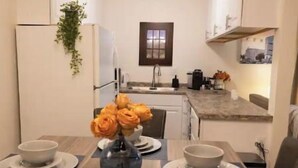 A modern kitchen with white cabinets, a central island, and a dining table set with plates and bowls.