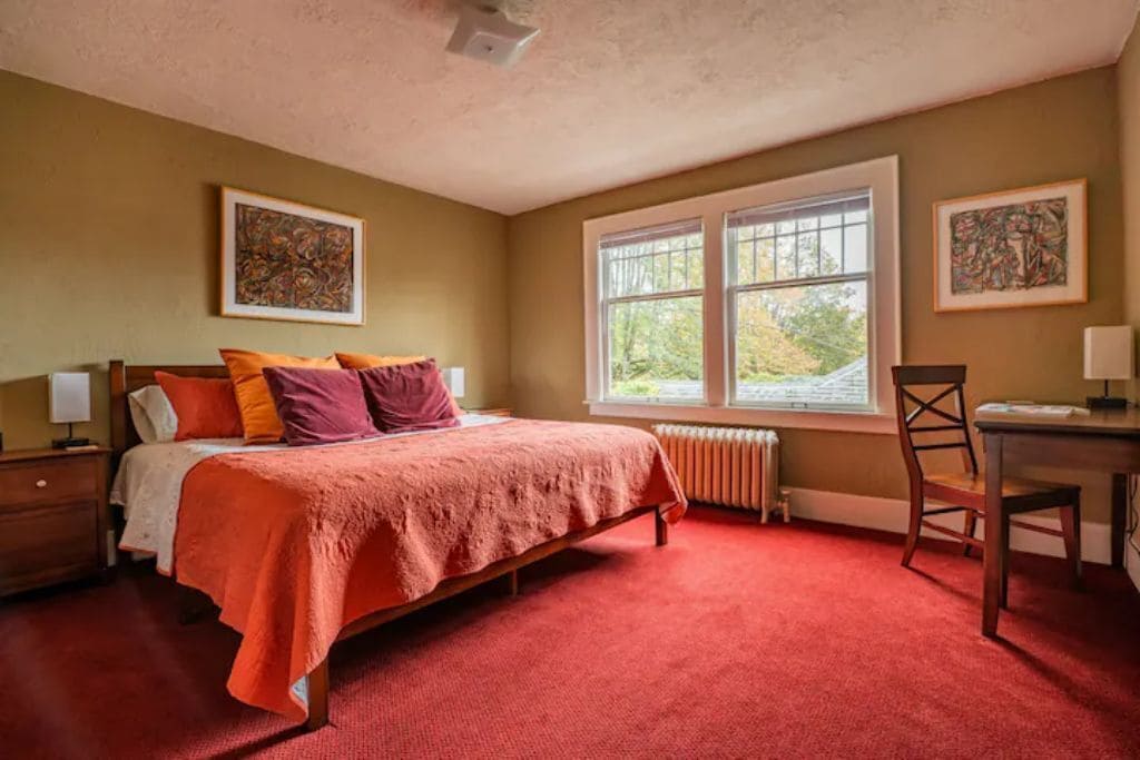 Un dormitorio con una cama, un escritorio y dos ventanas.