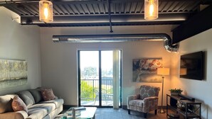 Un salon moderne avec un canapé, un fauteuil, une table basse en verre et un téléviseur posé sur un meuble.
