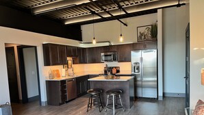 Une cuisine moderne avec des meubles en bois foncé, des appareils électroménagers en acier inoxydable et un îlot central doté de tabourets.