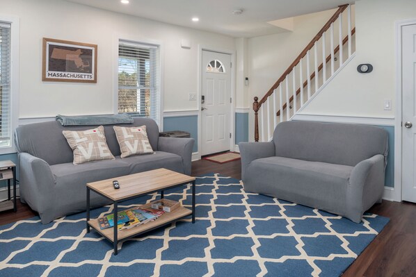 A living room with two grey sofas, a coffee table, and a patterned rug.
