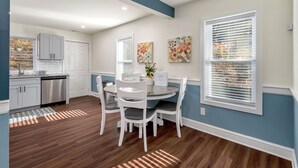 A modern kitchen with white cabinets, a dishwasher, and a dining area with a round table and chairs. - Beautiful Renovated Townhome w/parking (Holden)