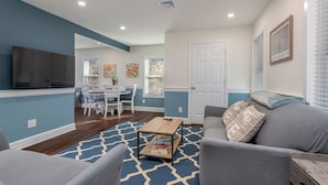 A modern living room with a sofa, armchairs, a coffee table, and a TV. - Beautiful Renovated Townhome w/parking (Holden)