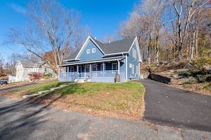 A two-story blue house with a front porch, a driveway, and a stone retaining wall. - Beautiful Renovated Townhome w/parking (Holden)