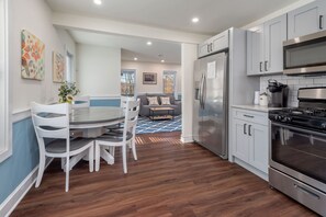 A modern kitchen with grey cabinets, a stainless steel refrigerator, and a black stove.